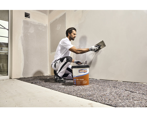 Handwerker beim Auftragen von Modulan Fill plus Finish Spachtelmasse auf eine Wand