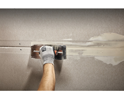 Handwerker verspachtelt eine Gipskartonwand mit einem Spachtel