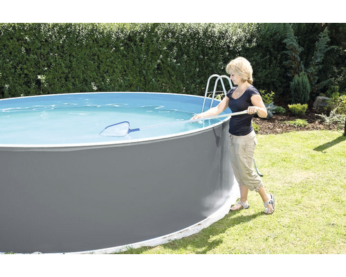 Frau reinigt runden Aufstellpool mit einem Kescher im Garten.