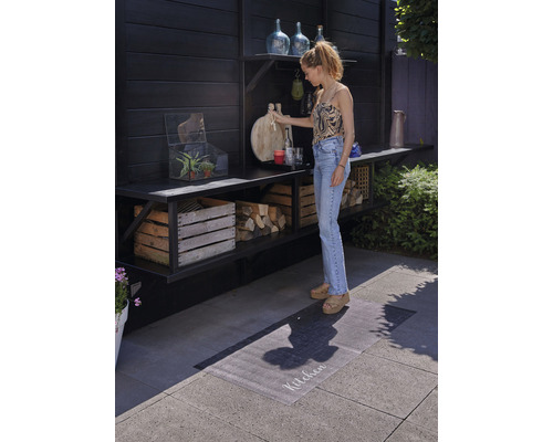 Szene mit einem Außenbereich mit Holzregalen, Dekorationen und einer Frau, die eine Schneidebrett hält.