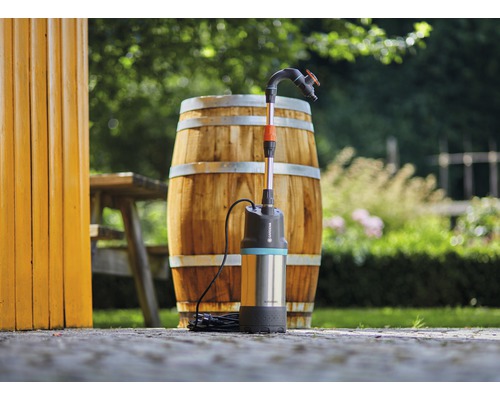 Pompe de récupération d''eau de pluie Gardena devant un fût en bois dans le jardin