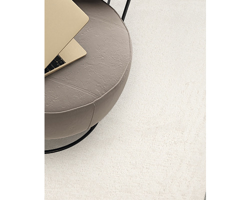 Vue détaillée d''un tapis clair à côté d''une table d''appoint avec ordinateur portable