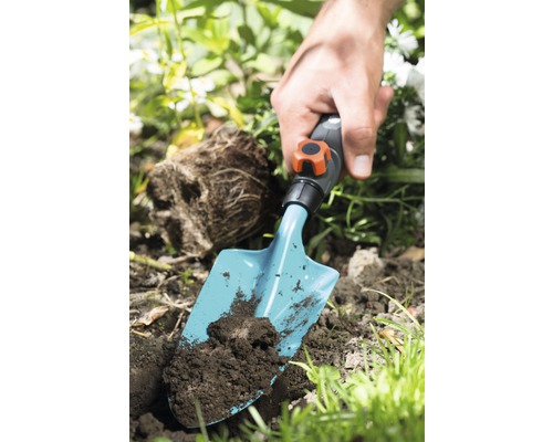 Personne plante avec une truelle dans la terre du jardin