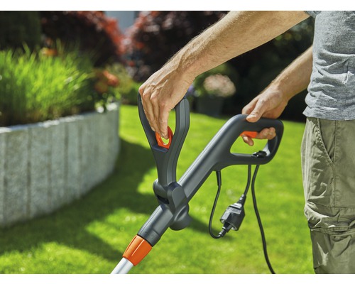 Detailaufnahme einer Person, die einen Rasentrimmer mit Kabel bedient