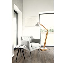 Pièce lumineuse avec fauteuil, lampadaire et petite table d''appoint sur plancher stratifié.