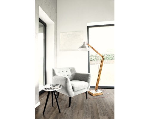 Pièce lumineuse avec fauteuil, lampadaire et petite table d''appoint sur plancher stratifié.