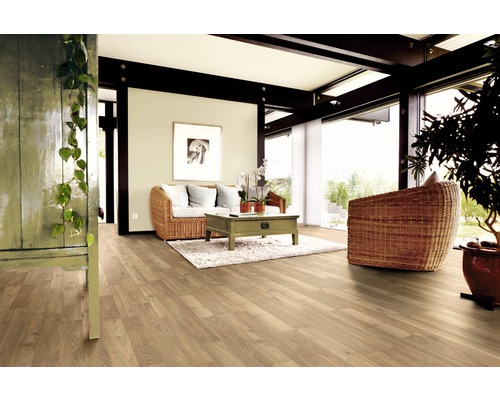 Salon lumineux avec parquet, fauteuil en rotin et table en bois sur tapis