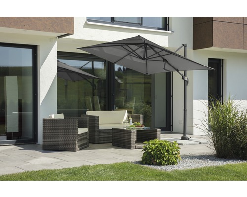 Gartenszene mit Ampelschirm, Rattansitzgruppe und Terrasse vor einem Wohnhaus