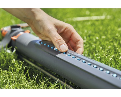 Une personne utilise un arroseur de gazon dans le jardin.