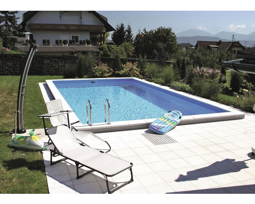 Piscine rectangulaire dans le jardin avec chaises longues et jouets gonflables