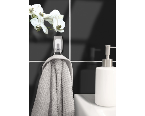 Scène de salle de bain avec serviette sur un crochet, distributeur de savon et une orchidée