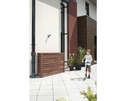 Récupérateur d''eau de pluie en bois pour l''arrosage du jardin avec un enfant en trottinette devant le mur de la maison