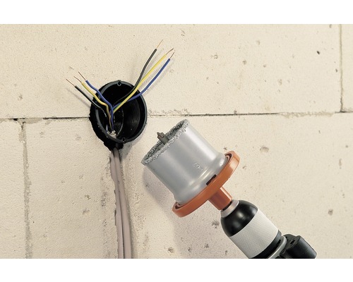 Perceuse avec scie cloche perçant un trou dans un mur pour un conduit électrique