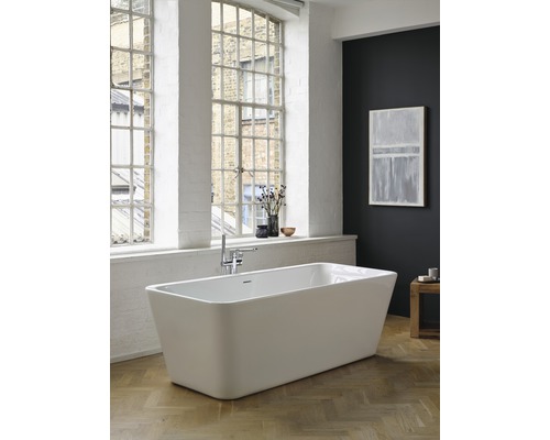 Baignoire îlot dans une salle de bains lumineuse avec de grandes fenêtres et un plancher en bois