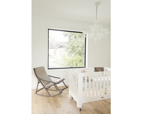 Helles Zimmer mit Babybett, Schaukelstuhl und Fenster