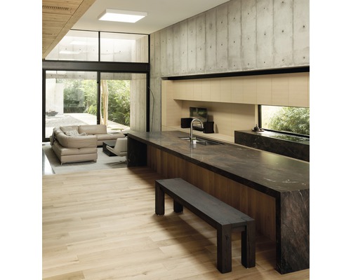 Heller, offener Wohnraum mit Kücheninsel, Sitzbank und Betonwand