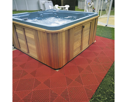 Bain à remous carré avec revêtement en bois et revêtement de sol rouge dans le jardin.