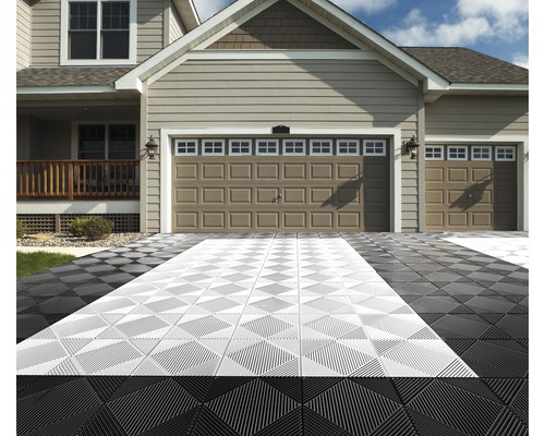 Einfahrt mit ineinandergreifenden Bodenfliesen vor einem Haus mit Doppelgarage