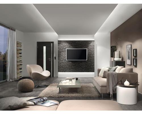 Wohnzimmer mit Sofa, Sessel, Couchtisch und Fernseher an einer Steinwand