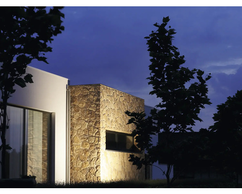 Außenansicht eines modernen Hauses mit Steinverkleidung und Fenster bei Nacht