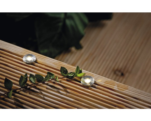 Deux spots de sol sont encastrés dans une terrasse en bois et brillent.