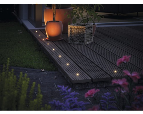 Terrasse avec plancher en bois, éclairée par des spots encastrés, ainsi que des pots de fleurs et des plantes