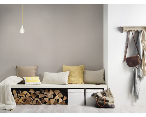 Pièce lumineuse avec banquette, coussins, bûches, boîtes de rangement, lampe, porte-manteau et sacs pour une atmosphère conviviale