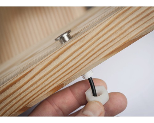 Gros plan sur une pièce de bois avec passage de câble et vis