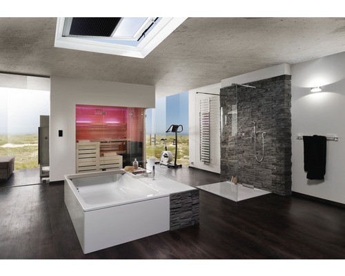 Helles Badezimmer mit Badewanne, Dusche, Sauna und Trainingsgerät vor großem Fenster