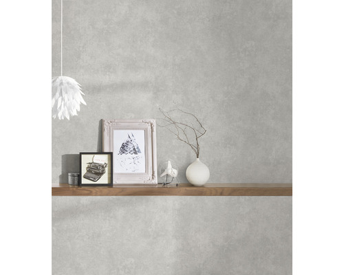 Wohnraum mit grauer Beton-Optik Tapete, dekoriert mit Regalboden, Lampe, Bildern und Vase