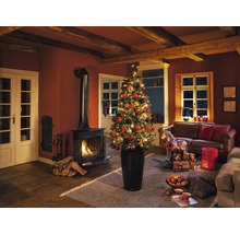 Ambiance de Noël dans un salon avec cheminée, canapé et sapin de Noël décoré dans une jardinière.
