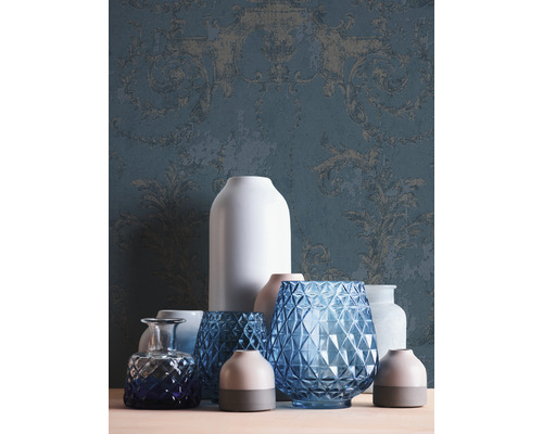 Arrangement décoratif de différents vases devant un papier peint à motifs.