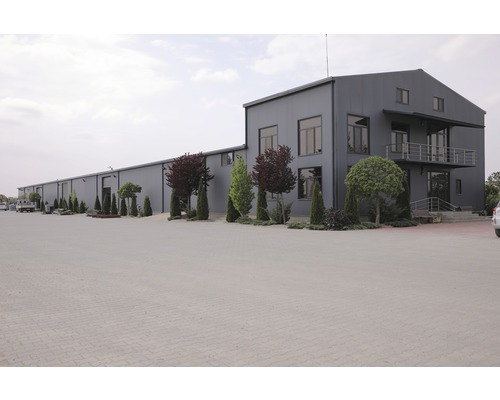 Aussenansicht eines grossen Industriegebäudes mit Parkplatz und Bäumen
