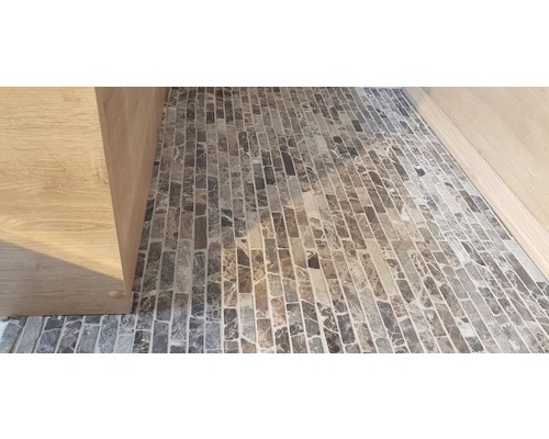 Detailansicht eines Bodens mit Mosaikfliesen und einem Holzschrank