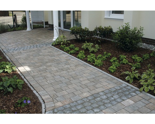 Chemin pavé menant à une maison avec parterres de fleurs