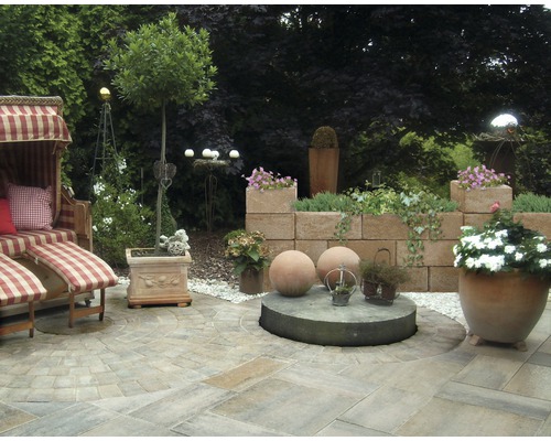 Gestalteter Gartenbereich mit Strandkorb, Pflastersteinen und Bepflanzung