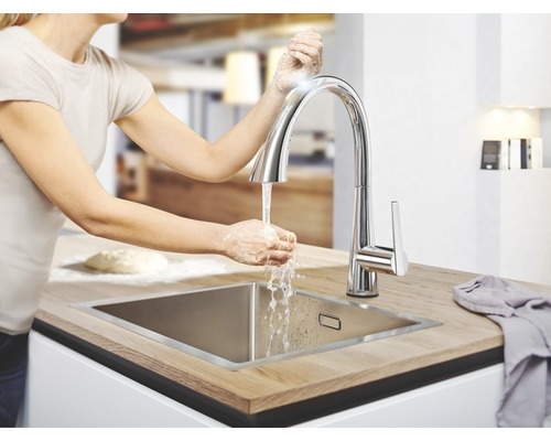Femme se lave les mains sur un évier de cuisine avec robinet