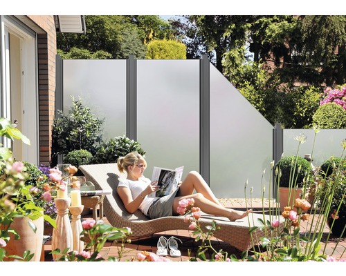 Terrasse mit Sichtschutzelementen, Gartenmöbeln und Frau auf einer Sonnenliege