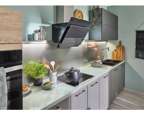 Cuisine lumineuse avec hotte aspirante, évier et plaque de cuisson.