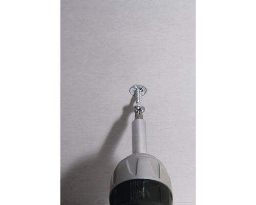 Un tournevis visse une vis dans un mur.