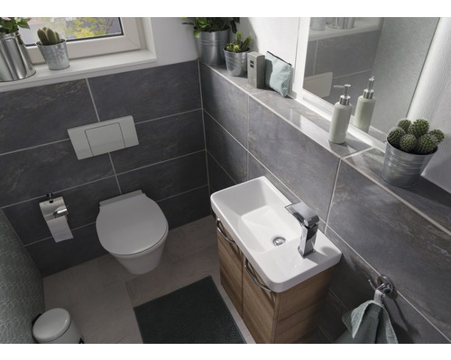 Helles Badezimmer mit Toilette, Waschbecken und grauen Fliesen