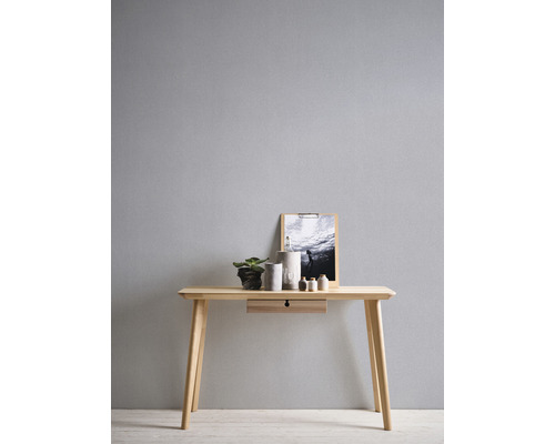 Un bureau en bois clair avec tiroir, décoré d''une plante, de récipients et d''une image.