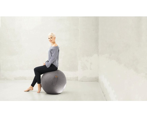 Femme assise sur un ballon de gymnastique au bureau.