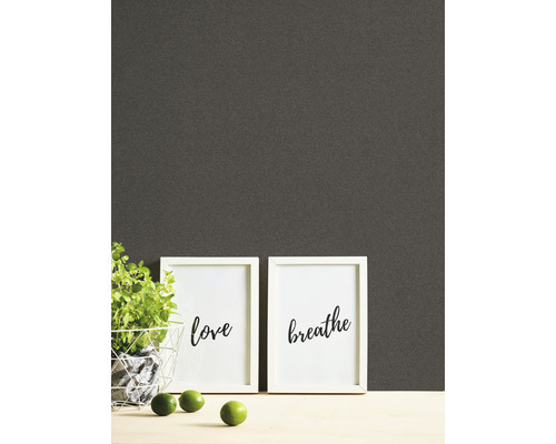 Tapete mit Pflanzen, Bilderrahmen mit Schriftzügen und Limetten auf einem Tisch