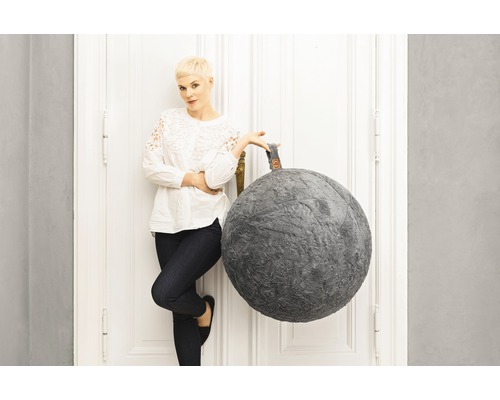 Pouf décoratif en forme de boule à côté d''une femme près d''une porte