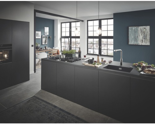 Helle, geräumige Küche mit Kochinsel, Spüle und Essbereich im Hintergrund.