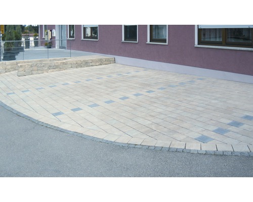 Gepflasterter Bereich vor einem Gebäude mit Steinmauer