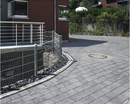 Aussenbereich mit Pflastersteinen, Metallzaun und Haus