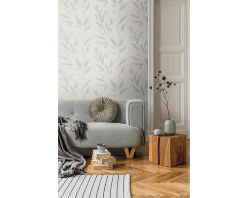 Wohnzimmer mit grauer Couch, Holztisch und Tapete mit Pflanzenmuster