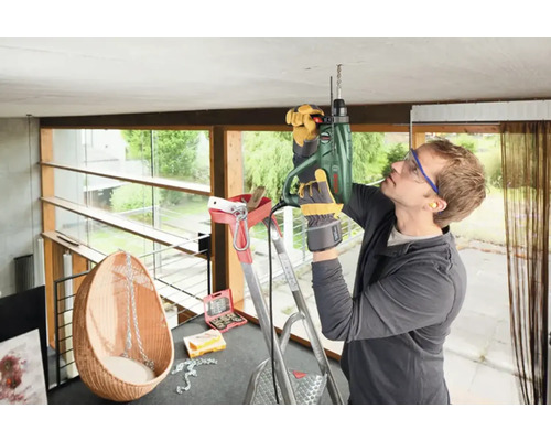 Un artisan perce le plafond d''une pièce avec une perceuse.